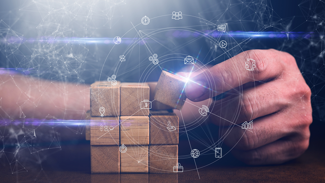 A hand placing a wooden block into a connected digital ecosystem, representing the integration of data, governance, and AI into a unified enterprise platform