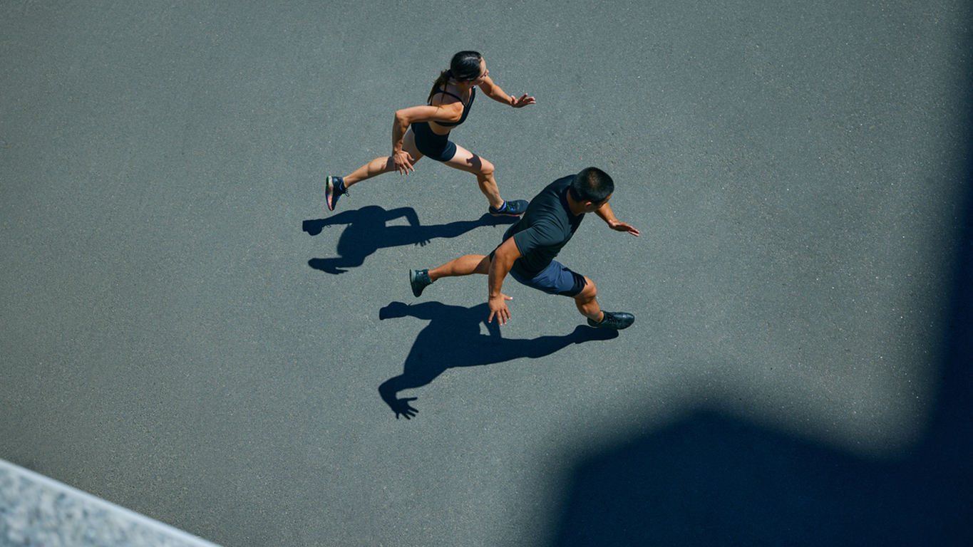 High-angle view of two people running, representing momentum and collaboration in development.
